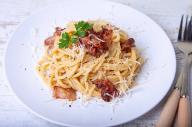 Pastırma, peynir Parmesan ve maydanoz ile Makarna carbonara. Geleneksel İtalyan yemeği. Yakın çekim, seçici odak.