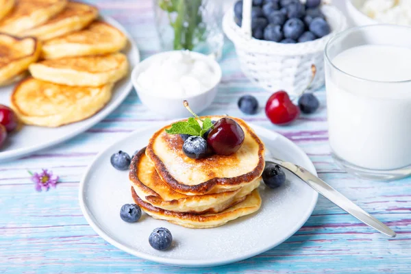 Cottage cheese pancakes (syrniki). Homemade cheesecakes from cottage cheese with sour cream, berries and milk. Traditional Russian dish. Close-up.