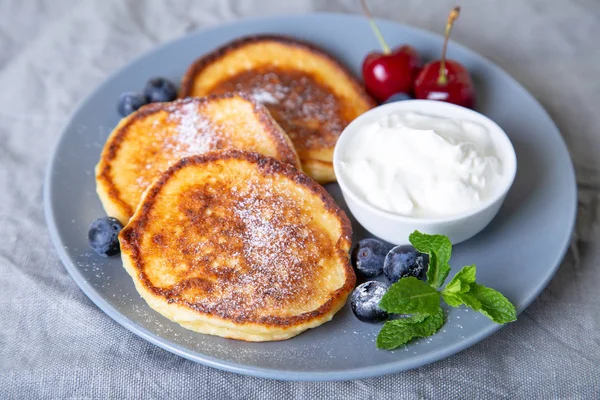 Cottage cheese pancakes (syrniki). Homemade cheesecakes from cottage cheese with sour cream and berries. Traditional Russian dish. Close-up.