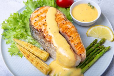Kızarmış somon, kuşkonmaz, mısırlı mini ve hollandaise soslu. Yakın plan..