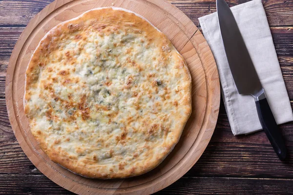 Peynirli ve otlu Osetya turtası (dereotu, maydanoz, soğan). Geleneksel Osetya usulü pişirme. Üst görünüm.