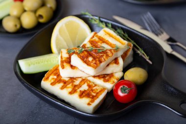 Siyah tavada ızgara haloumi peyniri, zeytin, domates, salatalık ve biberli. Yakın plan..