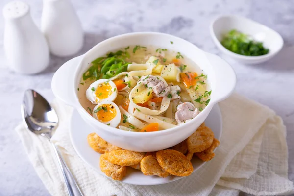 Soup with chicken, noodles, potatoes, quail eggs and carrots. Seasoned with onions and parsley. Close-up. — Stock Image Soup Chicken Noodles Potatoes Quail Eggs Carrots Seasoned Onions Parsley Royalty Free Stock Photos