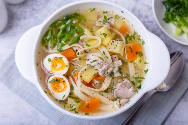 Soup with chicken, noodles, potatoes, quail eggs and carrots. Seasoned with onions and parsley. Close-up. — Stock Image Soup Chicken Noodles Potatoes Quail Eggs Carrots Seasoned Onions Parsley Stock Image