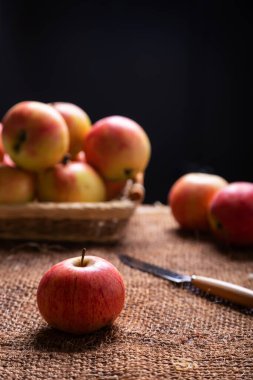 Çuval bezinde olgun elmalar ve siyah bir arka planda sepetin içinde. Arka ışıklandırma. Kırsal tarz, yakın plan..