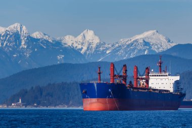 Arka planda tepeler ve dağlar ile Kargo Gemi