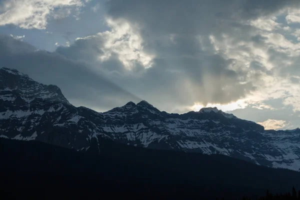 Сонце пробивається крізь хмари над гірським хребтом — стокове фото