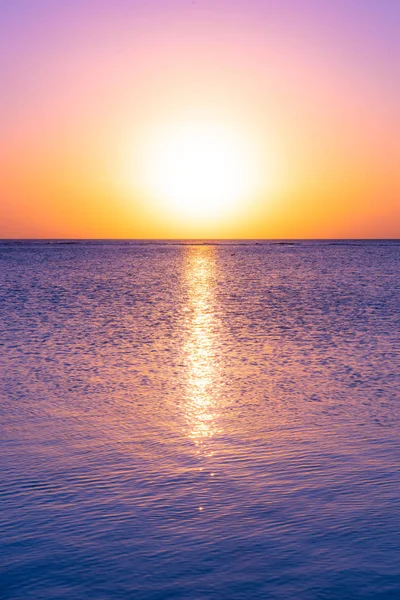 Sunset in holiday paradise resort on Mauritius island. Beautiful sunset light of sun going into the sea. Villas on the beach with private beach. Pink purple blue and orange red