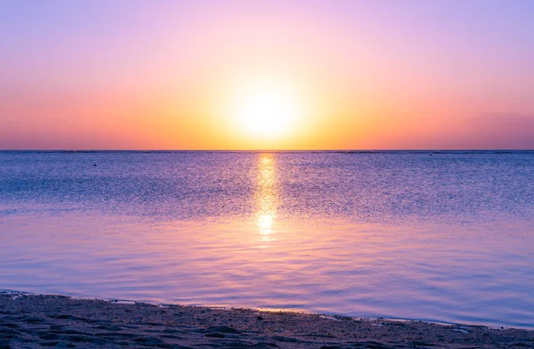 Sunset in holiday paradise resort on Mauritius island. Beautiful sunset light of sun going into the sea. Villas on the beach with private beach. Pink purple blue and orange red