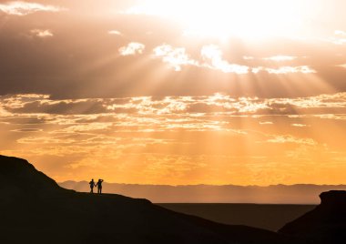 Romantik Çift el ele tutuşarak, romantik günbatımı güneş ray ile Moğolistan flaming cliffs üzerinden veri bloğu