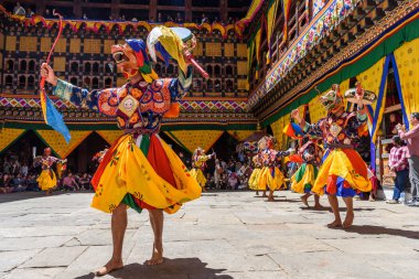 Buddhist Monk holding a drum, dancing monk at colourful mask dance at yearly buddhism Paro Tsechu festival in Bhutan monastery temple location. clipart