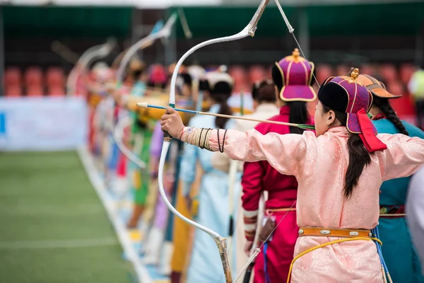 那达慕节蒙古射箭 蒙古妇女在传统蒙古礼服射击箭与蒙古弓和箭 五颜六色的传统服装在那达慕比赛7月 — 图库照片