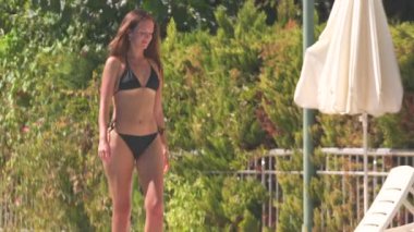 Genç kadın güneşlenmenin tadını çıkarıyor Aydınlık bir yaz gününde havuz kenarında