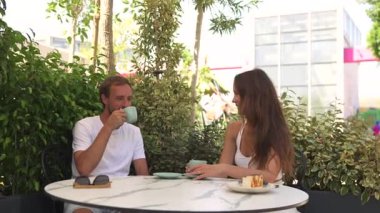 Romantik Çift Kahve İçiyor ve Barışçıl Yeşil Bir Ayarda Peynirli Kek Paylaşıyor