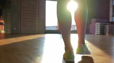 Yakından çekilen bir fotoğraf, büyük bir pencereye doğru ilerleyen, şık bir spor salonundan geçen ve azimli bir kızı yakalar. Atletik kıyafeti, spor yapmaya olan bağlılığını vurguluyor..