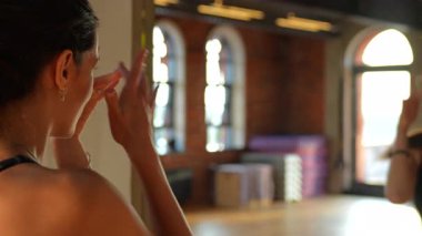 Siyah spor kıyafetli bir sporcu spor salonundaki aynaya yaklaşır, kamera hareketlerini pürüzsüz bir şekilde takip eder. Yansımasına hayran kaldıkça, sahne onun gücünü ve özgüvenini vurguluyor..