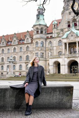 Eski binanın yanında şık bir model oturuyor.