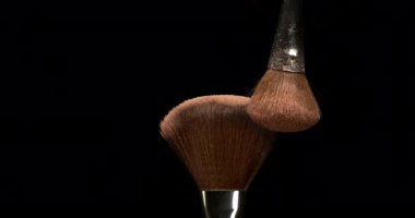 Makyaj fırçası siyah arka planda allık tozu yayıyor, yavaş çekim 4k