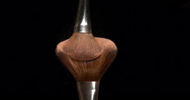 Makyaj fırçası siyah arka planda allık tozu yayıyor, yavaş çekim 4k