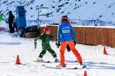 Sochi, Rusya Federasyonu - 7 Ocak 2018: Kadın kayak hocası Gorki Gorod kış dağ kayak merkezinde karlı dağ yamacında küçük kıza Kayak öğretir.