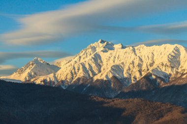 Ana Kafkasya ridge doğal karlı Chugush dağ tepe ve gün batımında mavi gökyüzü ile güzel kış dağ manzarası. Sochi, Rusya Federasyonu