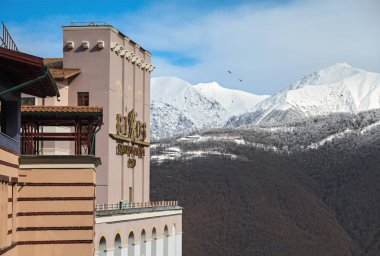 Sochi, Russia - February 19, 2014: Modern Rixos Krasnaya Polyana hotel of Gorky Gorod winter ski resort fronts on beautiful sceneries of snowy Caucasus mountain peaks. Scenic landscape