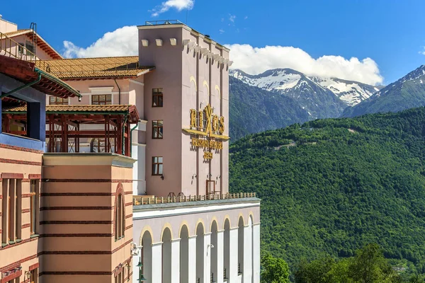 Sochi, Rusya - 7 Haziran 2015: Modern Rixos otel binası Gorki Gorod dağ kayak merkezi yeşil orman, karlı dağ zirveleri ve mavi gökyüzü yaz arka plan, güzel güneşli manzara