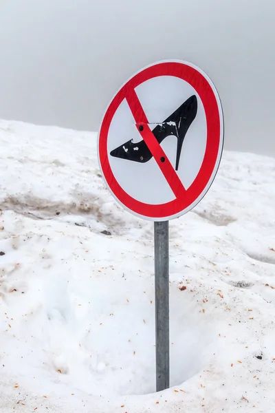 Prohibition sign forbidding women to walk on deep snow wearing shoes with spike heels.