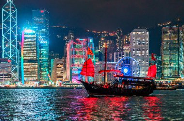 Hong Kong, Çin - 18 Ocak 2016: Hong Kong Hong Kong Adası'nın Victoria Limanı arasında Tsim Tsa Tsui waterfront görüntülendi şehir ışıkları ile manzarası. Gece cityscape arka plan üzerinde yelken önemsiz