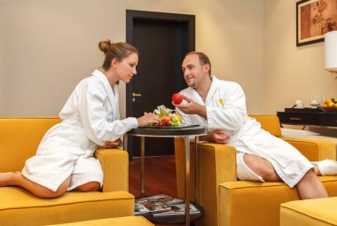 Genç mutlu beyaz iki beyaz bornoz spa balayına sonra meyve sahip sonra evlendim. Sadece Adam bir kez cennette Eva cazip kadına bir elma adam sunuyor