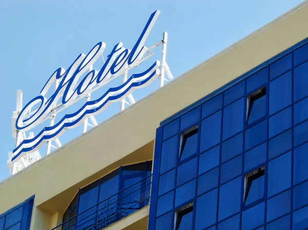 Hotel exterior sign on building roof on blue sky background