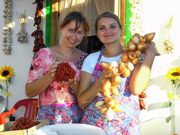 Dos bellas mujeres del país caucásico sonrientes muestran productos agrícolas producidos en su granja en el Foro Económico Internacional de Rusia — Foto de Stock