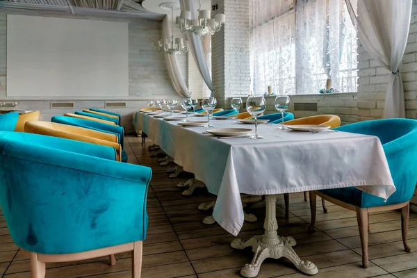 Mesa larga con cubiertos y sillones de colores en el restaurante iset para la comida. Luz ambiental vista interior — Foto de Stock