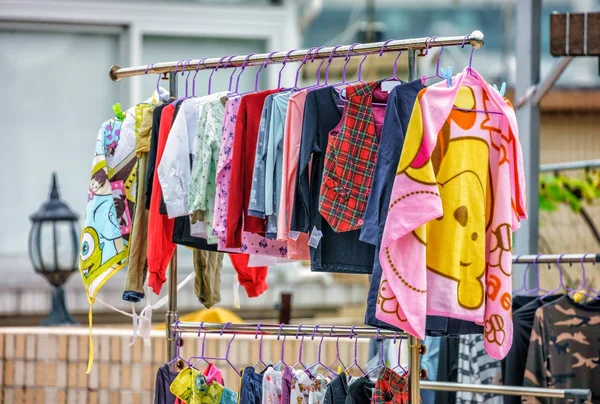 Varios coloridos niños ropa suspendida para secar después de lavar al aire libre en una barra de rack por perchas es una característica típica de la vida suburbana de la ciudad de Hong Kong —  Fotos de Stock