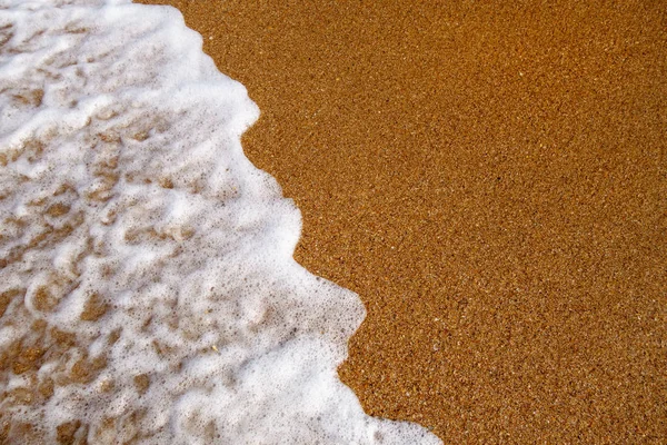 Spuming agua de mar surfeando sobre arena marrón atardecer fondo — Foto de Stock