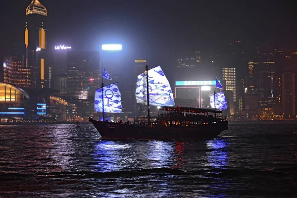 Hong Kong dzsunka ábrázol régi hagyományos érték-ból város. Éjszaka Vértes kilátás Aqua Luna II szemét tele turisták Tsim Sha Tsui a Hong Kong Skyline háttérben — Stock Fotó