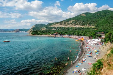 Anapa, Rusya-Temmuz 12, 2019: Bolshoy Utrish köyünde kara deniz kıyısındaki taşlı plaj parlak güneşli yaz gününde insanlarla dolu. Havadan görünüm