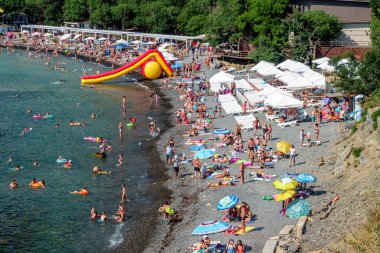 Anapa, Rusya-Temmuz 12, 2019: Bolshoy Utrish köyünde kara deniz kıyısındaki taşlı plaj parlak güneşli yaz gününde insanlarla dolu. Havadan görünüm