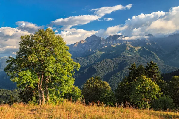 Красивый живописный летний осенний пейзаж пика Агепста и долины реки Мзымта в Кавказских горах в Сочи на закате. Солнечно-голубое небо с облаками — стоковое фото