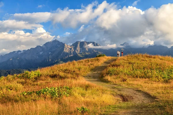 Красивый живописный летний осенний пейзаж пика Агепста и долины реки Мзымта в Кавказских горах в Сочи на закате. Солнечно-голубое небо пейзаж с облаками и людьми вдали — стоковое фото