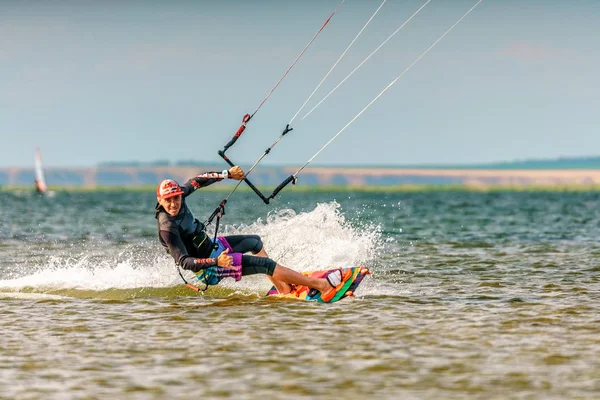 Man kitesurfer rides kite splashing on Bugaz firth at Black Sea coast on sunny day having fun and showing sign. Popular kitesurf destination — Stock Photo, Image