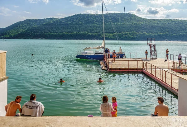 Mensen hebben rust en zwemmen in Abrau Mountain Lake. Scenic Cuacasus Mountain Forest Lake landschap op zonnige zomerdag. Recreatieve activiteiten op vakantie — Stockfoto