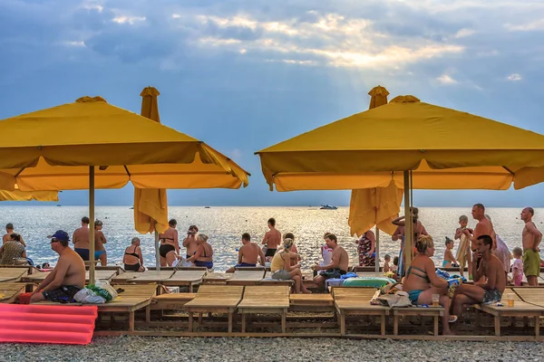 Menschen ruhen sich am steinigen Strand der Schwarzmeerküste bei Sonnenuntergang unter Zelten aus — Stockfoto