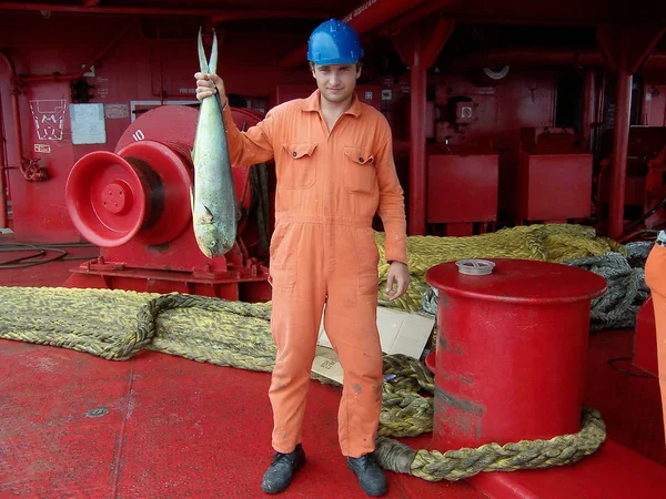 Mar Caribe, México - 25 de junio de 2015: Marinero en uniforme muestra su captura afortunada - pez gordo capturado en el océano desde la cubierta del buque petrolero — Foto de Stock