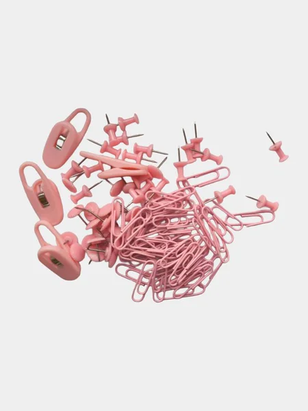  Beyaz bir yüzeye saçılmış, ataçlar, raptiyeler ve klasörler içeren bir grup pembe ofis malzemesinin yakın çekim görüntüsü.