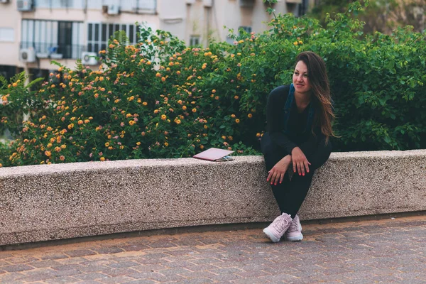Νεαρή Γυναίκα Στο Πάρκο Κάθεται Ένα Πέτρινο Παγκάκι Δίπλα Ένα — Φωτογραφία Αρχείου