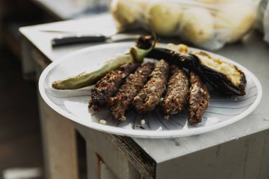 Pişmiş kebaplar, yeşil acı biber ve açık havada tek kullanımlık tabakta patlıcan. Yaz barbeküsü pişirme. Terasta barbekü. Parti zamanı, boş zaman. Hazır yemek. Sokak yemeği.. 