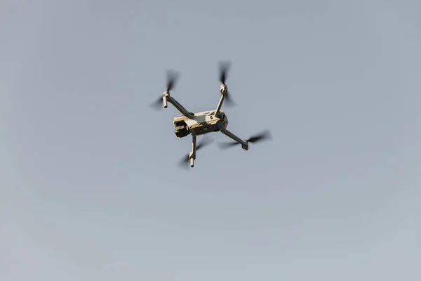 Grey drone with digital camera. Drone hovering in blue sky. Radio control helicopter. Closeup drone flying. Modern technology for photographing and filming bird\'s eye view. Professional photographe