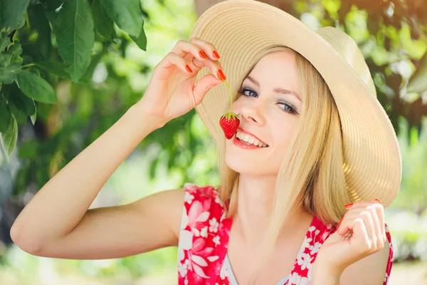 庭の夏の晴れた日 暖かい夏のイメージ 自己ケアと健康的なライフ スタイルを引き締めに笑みを浮かべてイチゴを食べて若いブロンドの女性 — ストック写真