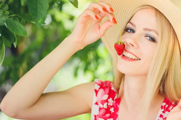 庭の夏の晴れた日 暖かい夏のイメージ 自己ケアと健康的なライフ スタイルを引き締めに笑みを浮かべてイチゴを食べて若いブロンドの女性 — ストック写真